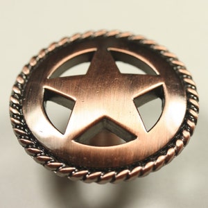 May include: A copper-toned metal cabinet knob with a rope-like border and a five-pointed star cutout in the center.