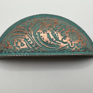 May include: A half-round, copper-toned cabinet pull with a turquoise blue patina and an intricate embossed floral design.