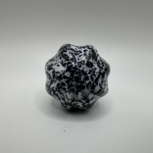 May include: A black and white speckled stress ball with a textured surface.