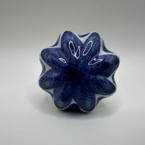 May include: A blue and white ceramic flower-shaped knob with a textured surface.