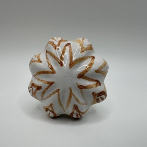 May include: White ceramic knob with a brown starburst design.