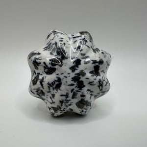 May include: A white and black speckled, star-shaped, ceramic object.