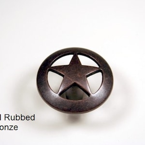 May include: Oil rubbed bronze cabinet knob with a star design. The knob is round with a star cut out in the center. The finish is a dark, rustic bronze color. The text "Oil Rubbed Bronze" is below the knob.