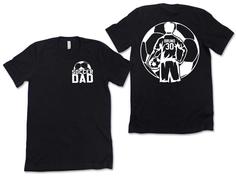 Puede incluir: Camisetas negras con dise&ntilde;os gr&aacute;ficos blancos. Una camiseta presenta "SOCCER DAD" con un bal&oacute;n de f&uacute;tbol. La otra camiseta muestra un jugador de f&uacute;tbol dentro de un bal&oacute;n de f&uacute;tbol con el nombre "Bruno" y el n&uacute;mero "30".