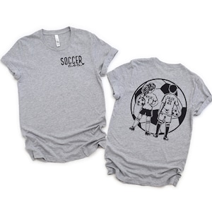 May include: Two gray t-shirts with a soccer theme. The front shirt says "Soccer Mom" and the back shirt has a graphic of two kids playing soccer with the names "Kylie 1" and "Caleb 21" on their jerseys.