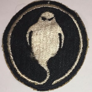 May include: A white ghost embroidered on a black circle patch with a white outline. The patch is circular and has a tan backing.