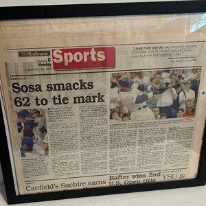 May include: A black and white newspaper clipping with the headline "Sosa smacks 62 to tie mark". The article is about baseball player Sammy Sosa hitting his 62nd home run of the season. The image also includes a photo of Sosa hitting a home run.