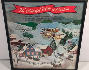 May include: A vintage vinyl record album cover featuring a winter wonderland scene with a red banner that reads "The Wonderful World of Christmas". The cover features a snowy village with houses, trees, and people enjoying winter activities. The album features Bing Crosby, Anne Murray, Glen Campbell, Tony Orlando, Dinah Shore, Bobby Vinton, Nat King Cole, Tennessee Ernie Ford, The New Christy Minstrels, and The Hollywood Pops Orchestra.