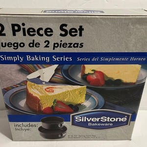 May include: A box set of SilverStone bakeware, featuring two springform pans. The box is gray with the text "2 Piece Set" and "Simply Baking Series." The image on the box shows cheesecake slices with strawberries and blueberries.