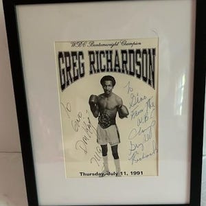 May include: A framed black and white photograph of WBC Bantamweight Champion Greg Richardson in boxing gear. The print features the text "WBC Bantamweight Champion", "GREG RICHARDSON", and "Thursday, July 11, 1991", along with handwritten ink signatures.