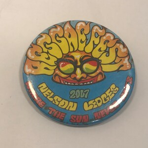 May include: A blue and yellow button with a cartoon sun wearing sunglasses and the text "Seafest 2007 Nelson Ledges Where The Sun Never Sets"