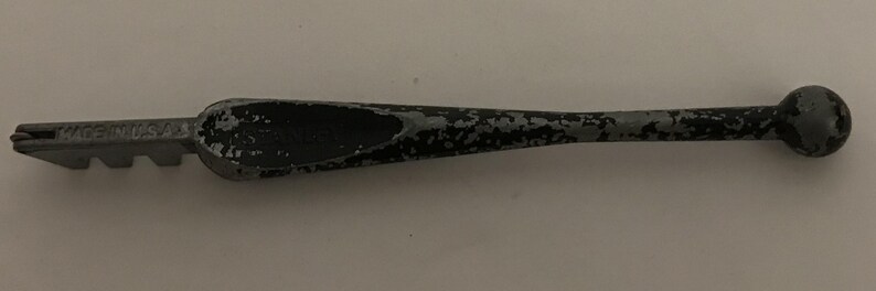 May include: A glass cutter with a gray and black handle and a cutting head. The text "MADE IN U.S.A." is visible on the cutting head. The tool is designed for cutting glass.