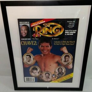May include: A framed September 1992 issue of The Ring magazine featuring a central portrait of boxer Julio Cesar Chavez with his arms raised. The cover includes smaller portraits of other boxers, the title text, and headlines in black and white.