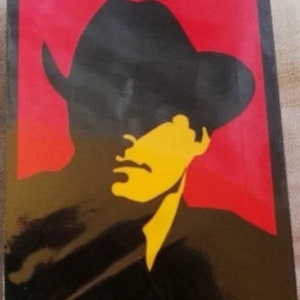 May include: A black and yellow silhouette of a person wearing a cowboy hat against a red background.