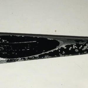May include: A glass cutter tool with a silver metal head and a black handle. The head has a series of small teeth for scoring glass. The handle has a worn, speckled appearance. The text "MADE IN U.S.A." is visible on the head.