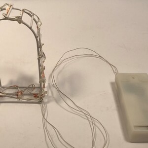 May include: White metal archway with white LED lights, battery pack and wires.