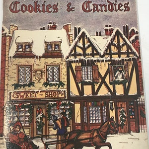 May include: A vintage Christmas cookbook cover with a colorful illustration of a snowy town scene. The cover features a horse-drawn sleigh, a sweet shop, and the text "Christmas Cookies & Candies".