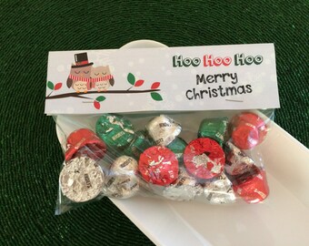Könnte beinhalten: Eine weiße Geschenktüte mit einem festlichen Weihnachtsdesign mit zwei Eulen, die Weihnachtsmützen tragen, und dem Text "Hoo Hoo Hoo Frohe Weihnachten". Die Tüte ist gefüllt mit kleinen, rot, grün und silber verpackten Schokoladen.