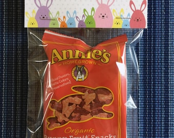 May include: A red and white bag of Annie's Homegrown Organic Bunny Fruit Snacks with a picture of a bunny rabbit on the front. The bag contains Summer Strawberry flavored snacks. The bag is 0.8 ounces (23 grams).