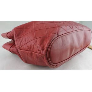 May include: A red quilted leather tote bag with a rounded bottom. The bag is made of a soft, supple leather and has a quilted design.