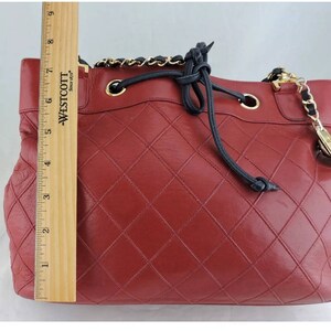 May include: A red quilted leather handbag with a black drawstring closure and a gold chain strap.