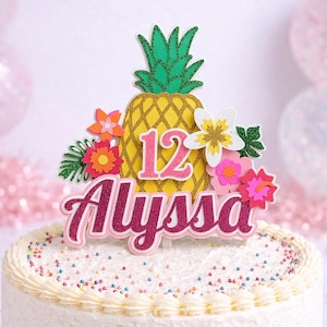 May include: A white frosted cake decorated with colorful sprinkles and a decorative topper. The topper features a yellow pineapple, the number 12, the name "Alyssa", and colorful flowers. The cake is on a white cake stand.