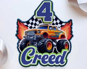 Könnte beinhalten: Ein mehrlagiger Tortenstecker aus Papier mit einer dunkelblauen Glitzerzahl 4 oben und dem Namen Creed in dunkelblauer Glitzerschrift unten. In der Mitte ist ein orangefarbener Monstertruck mit Flammen und einer Zielflagge abgebildet.