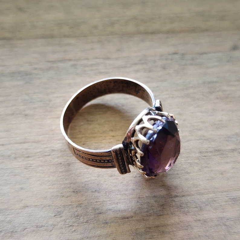 May include: A silver ring with a purple gemstone set in a gold crown-like setting.