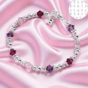 May include: A beaded bracelet featuring alternating silver-toned round beads and faceted crystal bicone beads in shades of deep purple and light pink. The bracelet includes a silver-toned letter R charm and a lobster claw clasp closure.