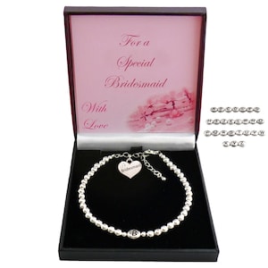 May include: A silver-toned beaded bracelet with a heart-shaped charm engraved with the word Bridesmaid and a single letter B bead, presented in a black box with the text For a Special Bridesmaid With Love and a set of alphabet beads.