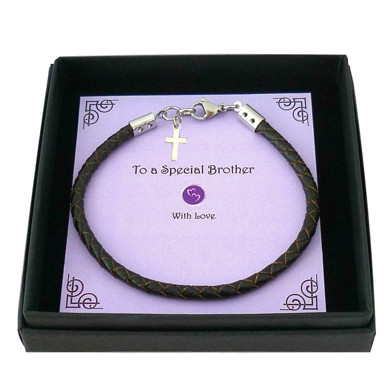 May include: A dark brown braided leather bracelet with a silver-toned metal cross charm and lobster clasp. The bracelet is displayed on a light purple card inside a black box, featuring the printed text "To a Special Brother" and "With Love".