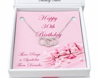May include: A sterling silver necklace with three interlocking twisted rings presented in a white gift box. The pink display card features the text Happy 30th Birthday and Three Rings to Symbolise Three Decades with floral accents.