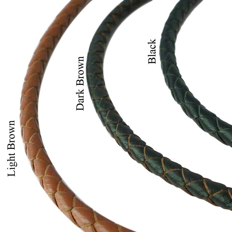 May include: Three braided cords arranged in a curved formation, labeled Light Brown, Dark Brown, and Black. Each cord features a consistent woven texture and rounded profile, showcasing the distinct color variations of the three individual strands.