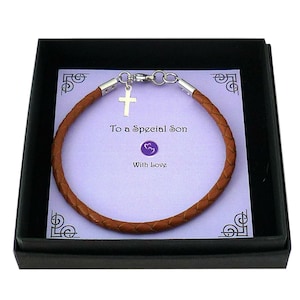 May include: A braided brown leather bracelet with a silver-toned cross charm and metal clasp, presented on a light purple card with the text To a Special Son and With Love, all contained within a black box.