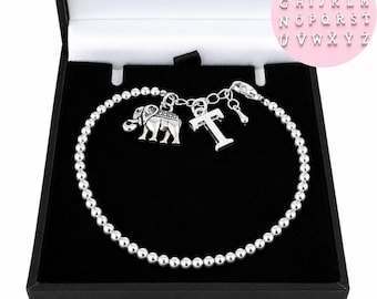 Puede incluir: Una pulsera de cuentas plateadas con un dije de elefante y un dije con la letra T. La pulsera se presenta en una caja negra. Un recuadro circular muestra el alfabeto completo de dijes de letras plateadas disponibles de la A a la Z.