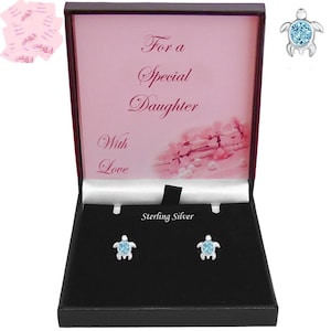 May include: A pair of sterling silver turtle stud earrings featuring light blue circular stones in a black presentation box. The box lid interior displays the text For a Special Daughter With Love and a floral graphic. A single earring is shown separately.