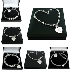 May include: Four silver bracelets with heart-shaped charms. The charms are engraved with different messages, including "Happy Birthday" and "Eva May". The bracelets are displayed in black boxes.