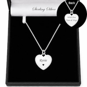 May include: A sterling silver heart-shaped pendant necklace on a delicate chain. The front of the heart is engraved with the name Rosie and a small heart icon. An inset shows the back of the pendant engraved with the text With love Nan & Pops.