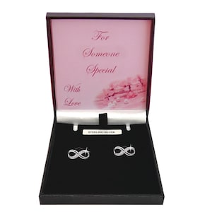 May include: A pair of sterling silver infinity stud earrings featuring small clear stones, presented in a black jewellery box. The inside lid displays the text For Someone Special With Love above a pink floral graphic and a small white label.
