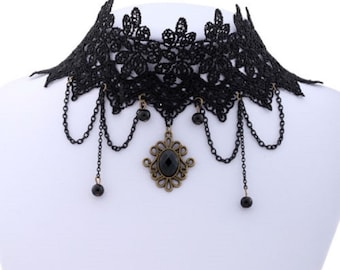 May include: Black lace choker necklace with a dangling pendant featuring a black gemstone and ornate metalwork. The necklace has multiple chains with black beads.