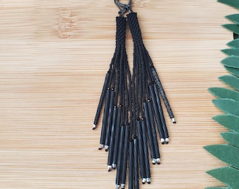 Pendientes largos con borlas negras lisas y flecos de cuentas.