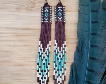 Pendientes de tapicería con flecos de cuentas de semillas en tonos marrón, verde azulado y crema.