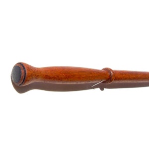 May include: A wooden wand with a dark brown handle and a black tip. The wand is made of a dark wood with a reddish hue.