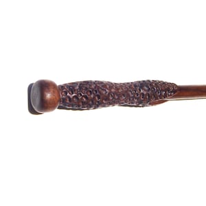 May include: A dark brown wooden wand with a textured surface and a rounded tip.