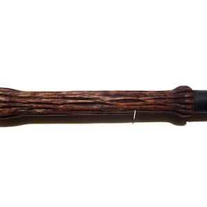 May include: A dark brown wooden wand with a black tip. The wand has a textured, bark-like surface.