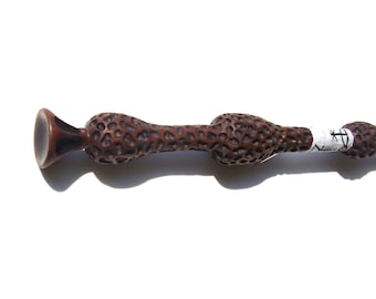 Peut inclure: Une baguette en bois brun avec une surface texturée et noueuse et une étiquette blanche avec une inscription noire. La baguette a une extrémité unique et bulbeuse.
