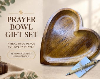 May include: A heart-shaped wooden bowl with three engraved crosses, accompanied by a pen and prayer cards. The text reads: PRAYER BOWL GIFT SET, A BEAUTIFUL PLACE FOR EVERY PRAYER, 15 PRAYER CARDS + PEN INCLUDED, and the pen says Pray Without Ceasing.