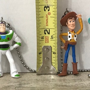 May include: A set of five Toy Story character pull chain light switch covers. The characters are Woody, Buzz Lightyear, Rex, Jessie, and Bo Peep. The characters are all in their signature poses and colors. The light switch covers are made of plastic and are easy to install.