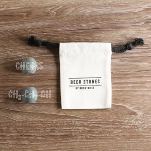 May include: Two gray stone coasters with the words "CHEERS" and "CH3-CH2-OH" on them. The coasters are in a white drawstring bag with the words "BEER STONES BY BREW MUSE" printed on it.
