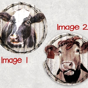 May include: Two round coasters featuring a cow's face with a barbed wire border. The first coaster features a black and white cow with a white patch on its forehead. The second coaster features a brown cow with a red bandana around its head.